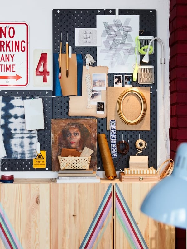 The source pegboard display combines artwork, notes, small objects, and hanging accessories above coordinated storage.
