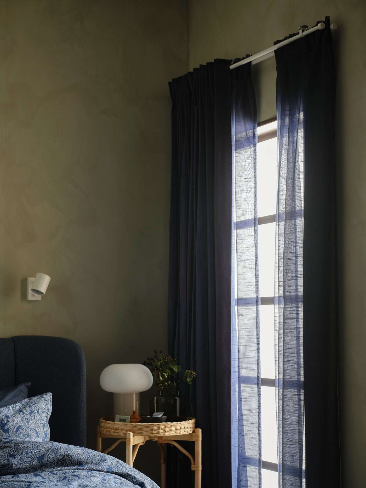 IKEA bedroom example showing a curtain rod and dark layers against green walls.