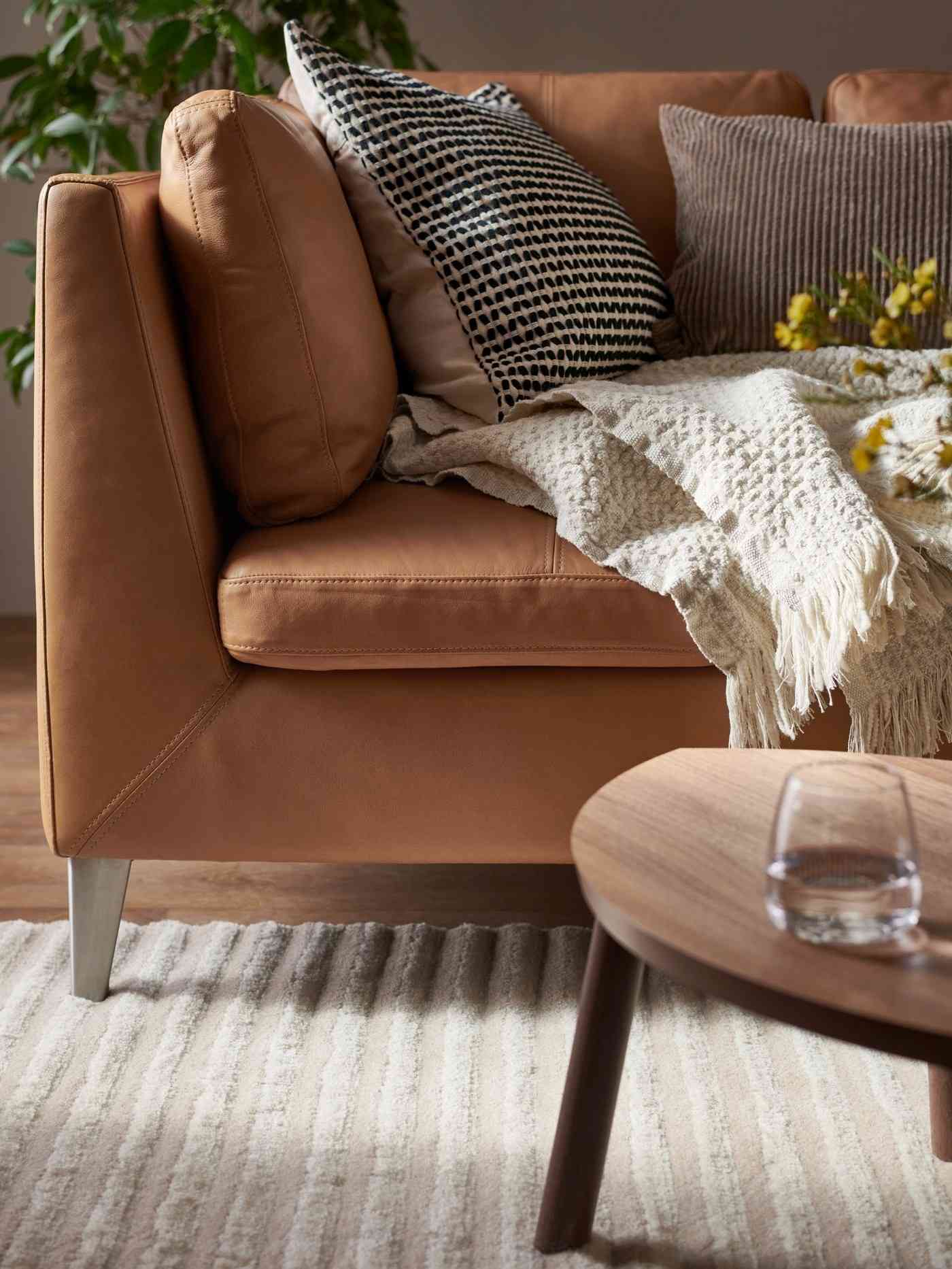 A source close-up contrasts brown leather with a softer throw and cushions in distinct woven textures.
