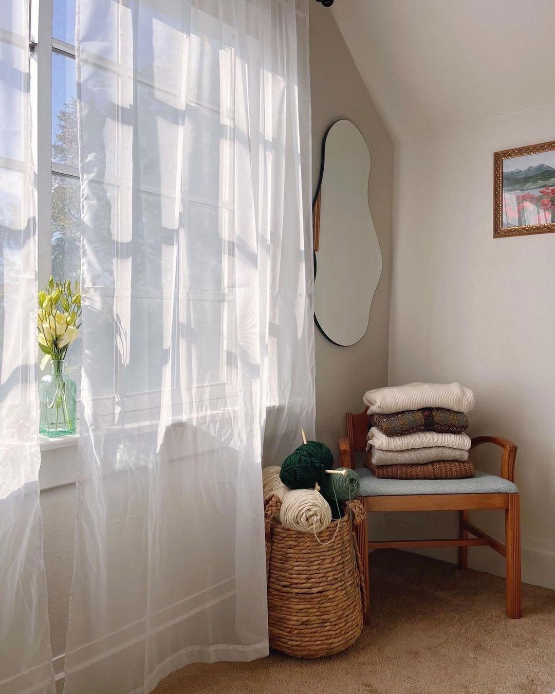 A separate source corner pairs a compact chair with folded textiles and a basket beside the window, illustrating a defined use for a secondary seat.
