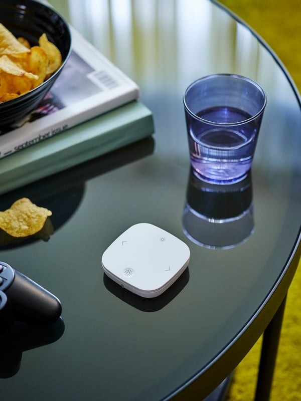 The source shows a lighting remote on a central table, illustrating an adjustable setting within the existing layout.