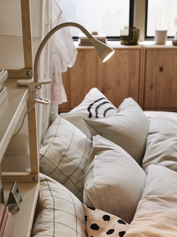 IKEA guest-room detail showing a clamp spotlight on shelving beside the sofa bed.