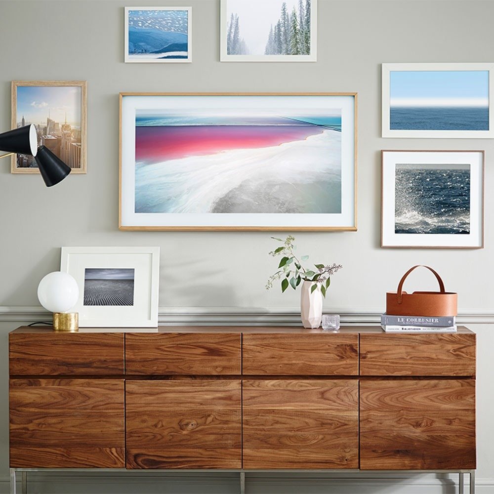 The reference shows a screen displaying artwork within a larger gallery arrangement above a timber cabinet.