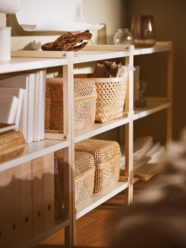 IKEA apartment detail showing open shelving with woven baskets, files, and lidded containers.
