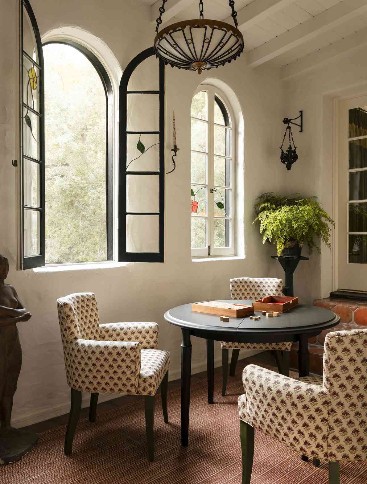 The project's games area places upholstered chairs around a table beside arched windows.