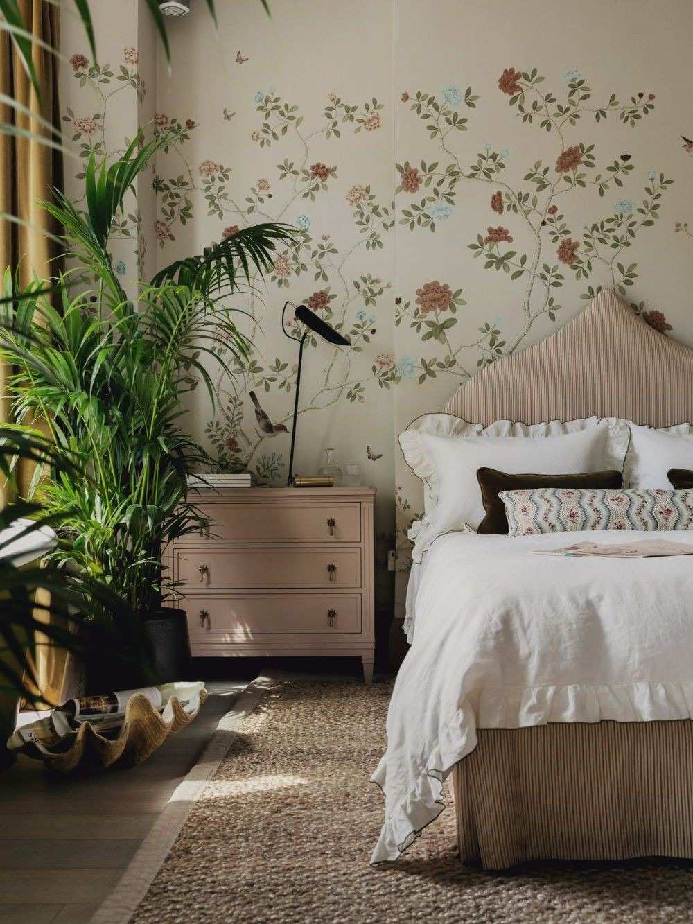A separate source bedroom layers a light bed skirt beneath striped bedding, relating the textile to a floral wall treatment.