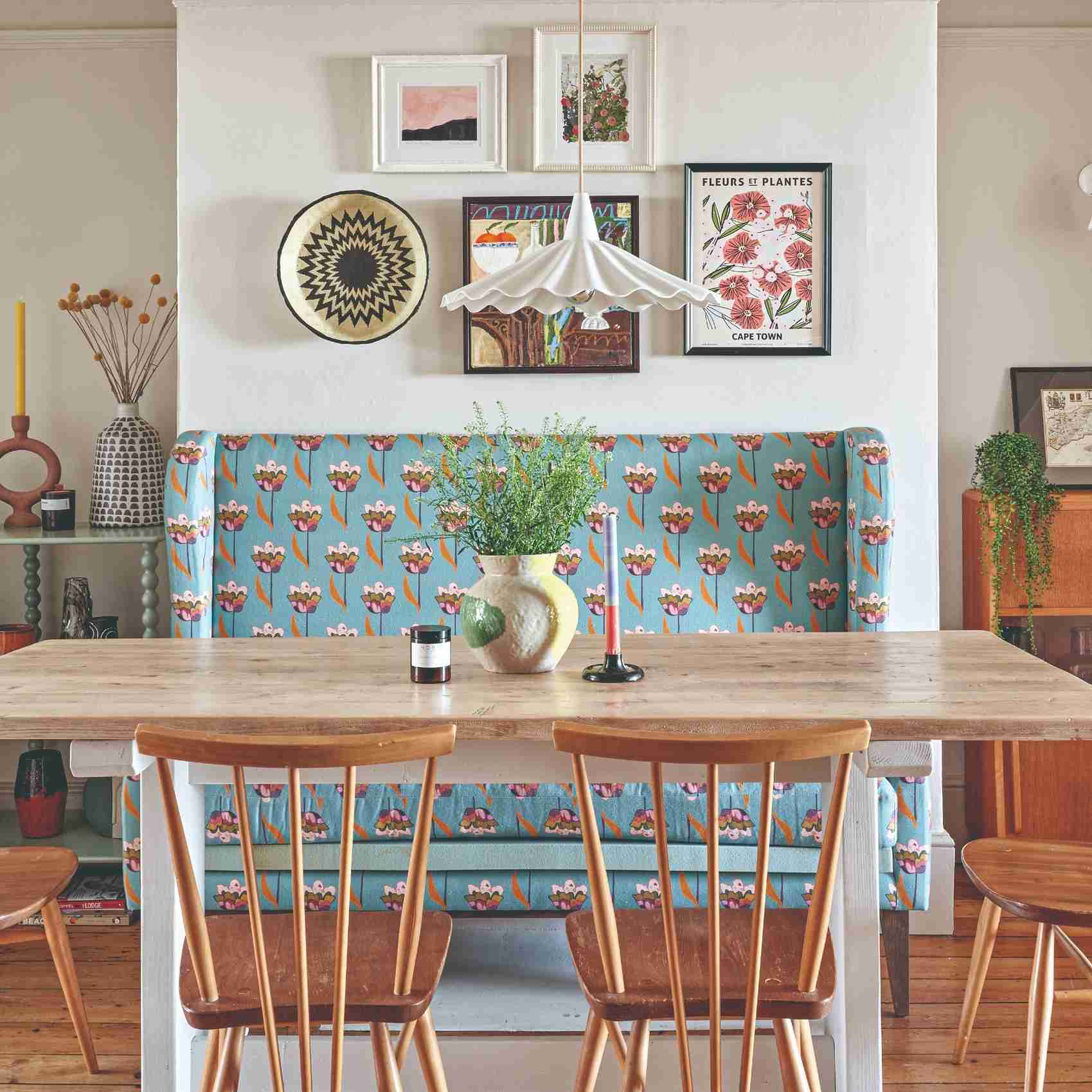 A source dining room combines a patterned upholstered banquette with a timber table and a pendant above the group.