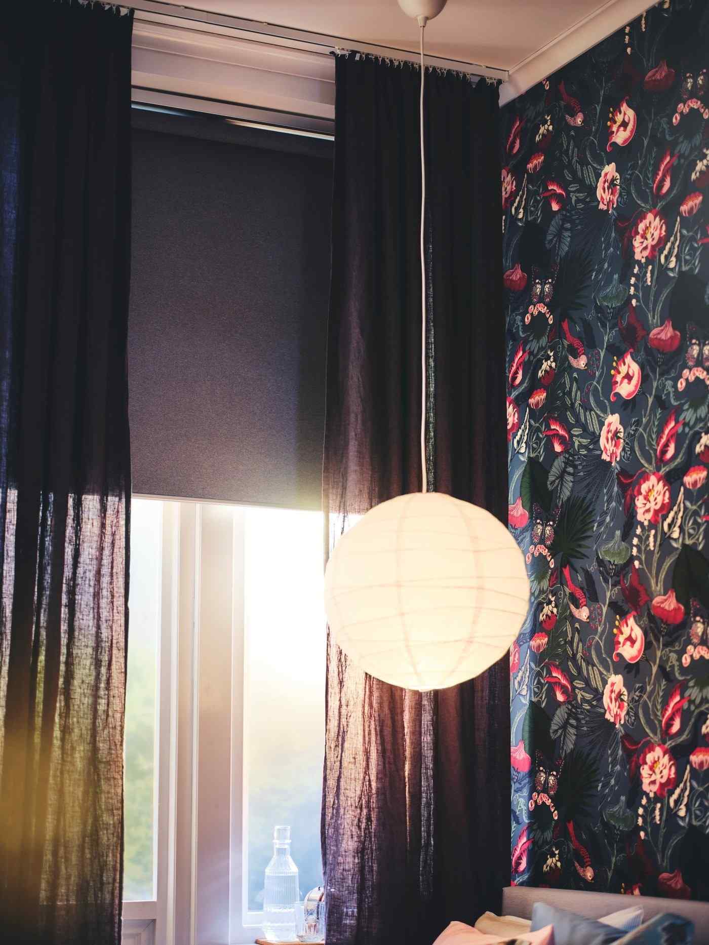 IKEA bedroom example showing dark curtain fabric around a window, with floral wallpaper beside it.