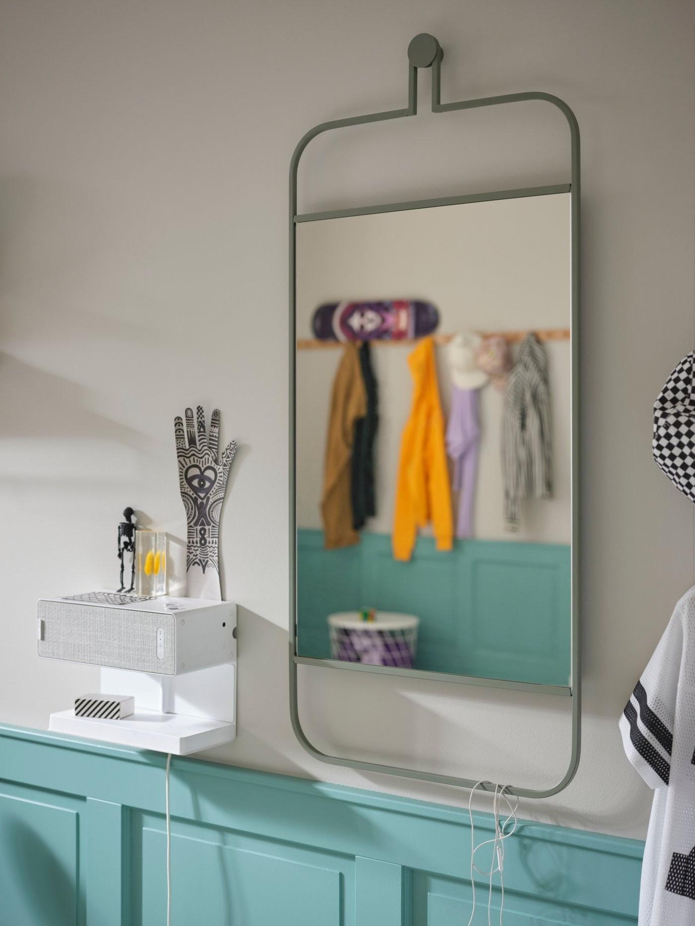 The source wall mirror reflects hanging clothes beside a small wall-mounted accessory surface in the teen bedroom.