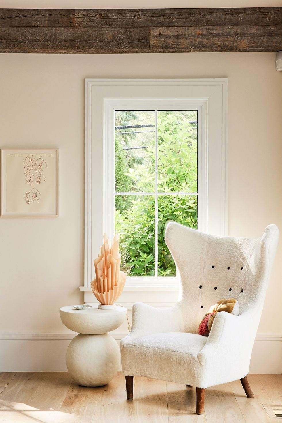 The source pairs a tall upholstered chair with a pale setting and a smaller supporting surface, illustrating softness beside rustic materials.