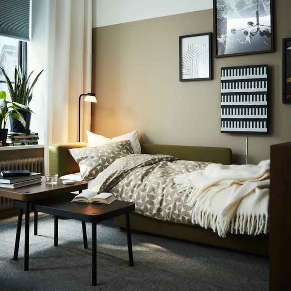 A separate source convertible sofa is shown prepared as a bed with bedding in place, illustrating an alternative sleeping configuration.