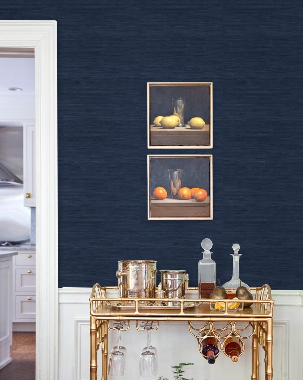 Society Social and WallPops faux-grasscloth wallpaper shown in navy behind a bar cart in the House Beautiful product feature.