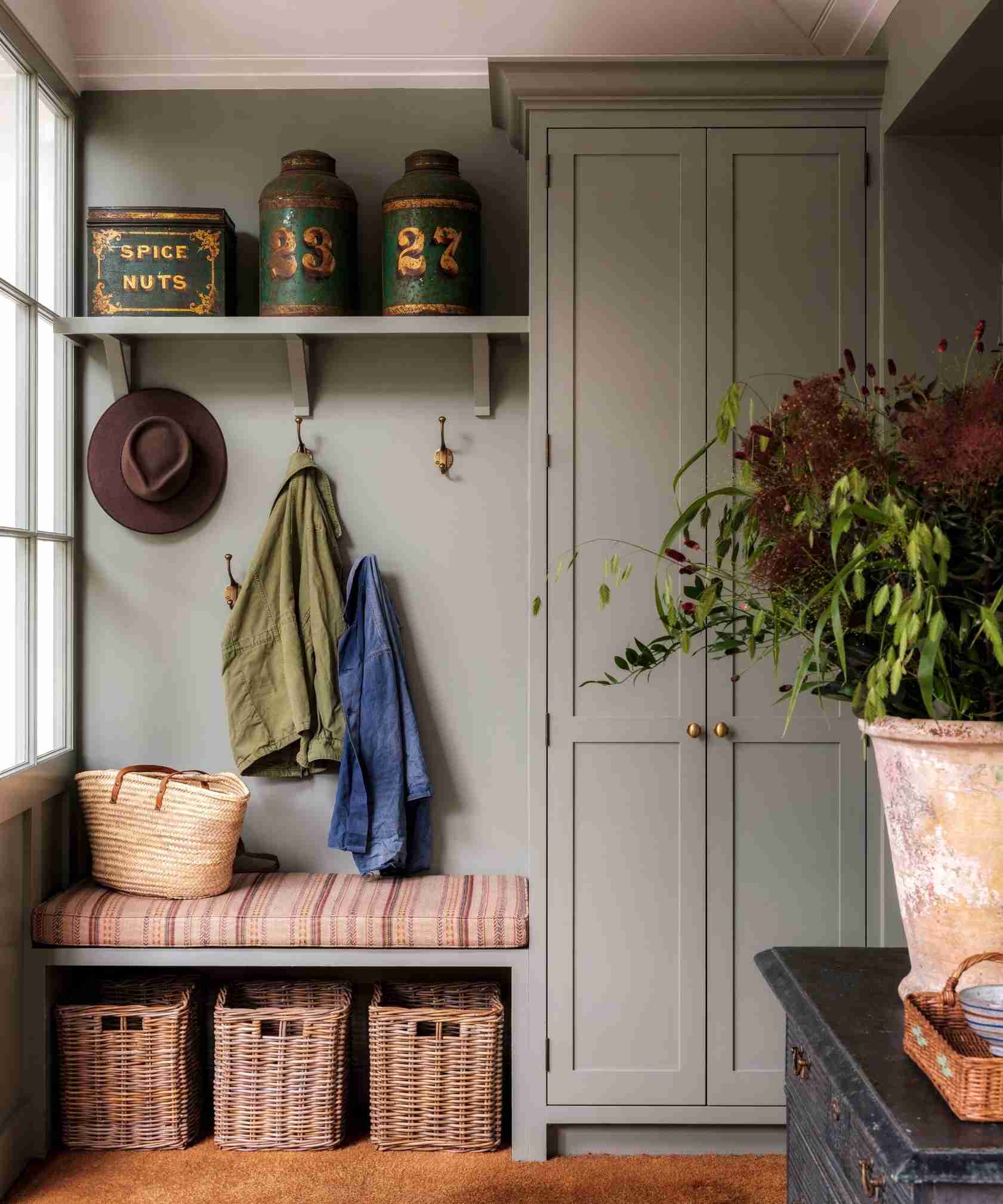 The reference combines a striped bench cushion, baskets below, wall hooks, and collected containers above in a different entrance setting.