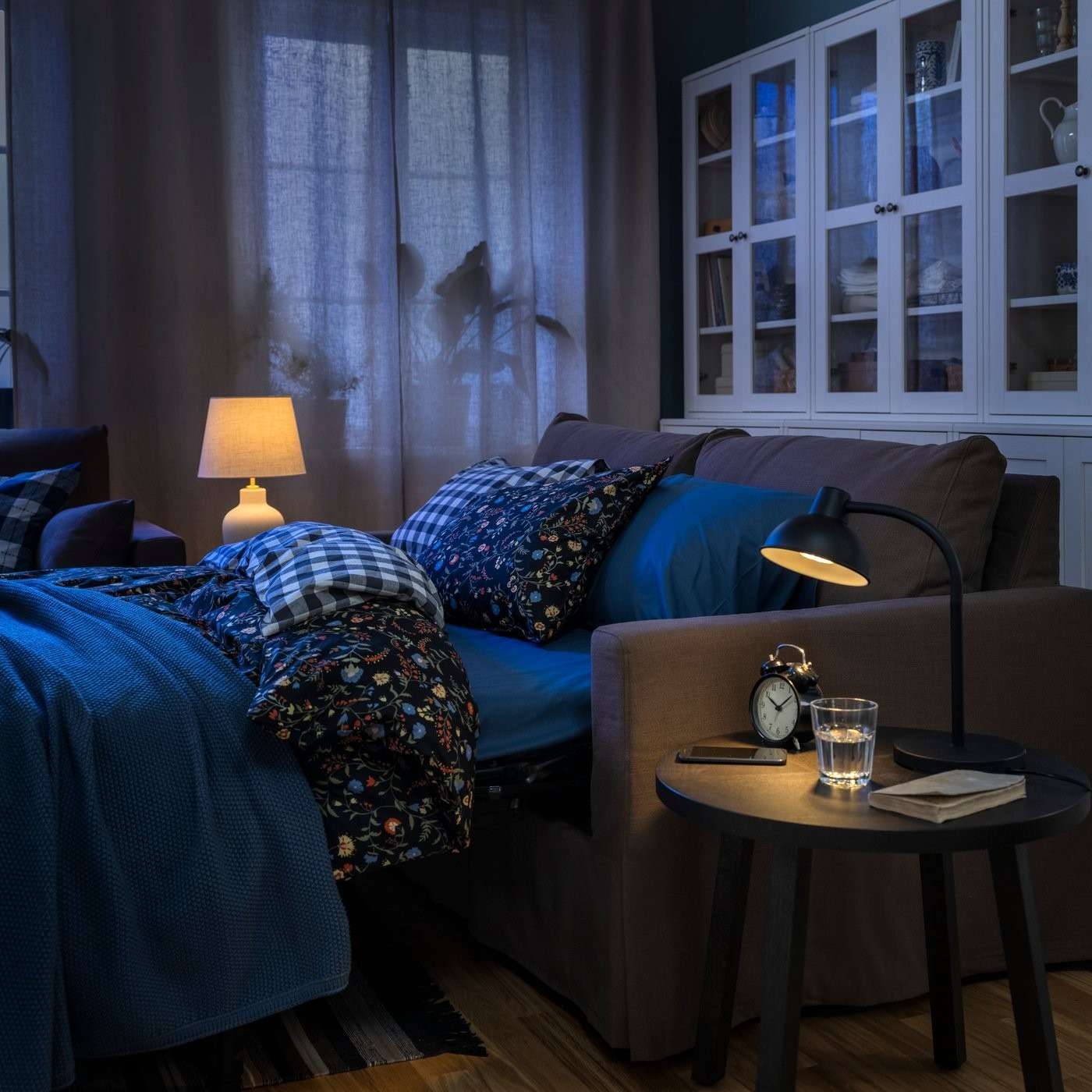The source sofa-bed is pictured in its sleeping configuration, with bedding in place beside the family-room storage.