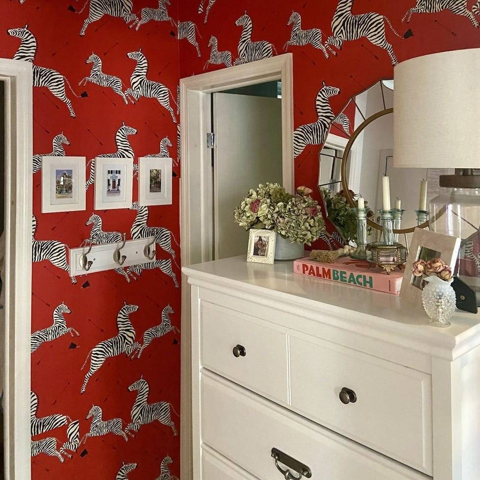 The source red zebra-wallpaper example repeats a bold pictorial motif around an entrance and dresser.