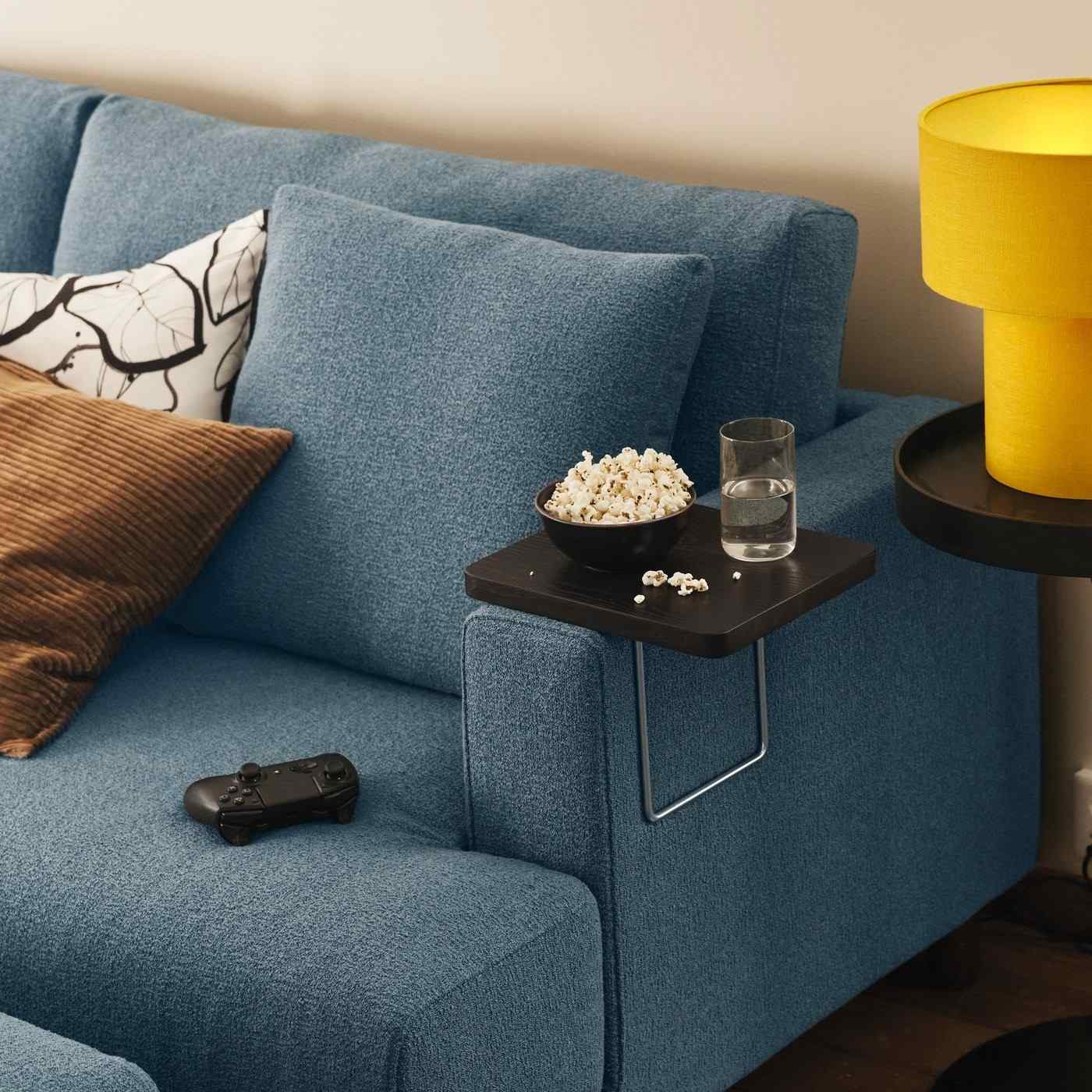 The source armrest tray is shown holding snacks and a drink on the modular sofa, illustrating a close supporting surface.