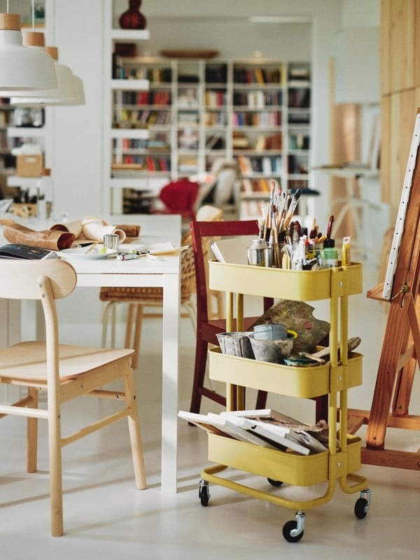 A separate source activity area places art supplies on a wheeled cart beside shared work tables, keeping those materials near their use.