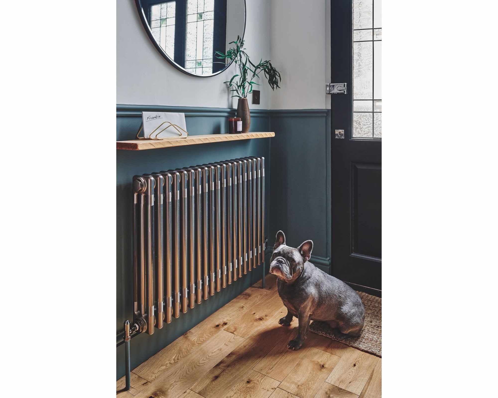 A separate source entrance combines a mirror and shallow wall-side surface beside a radiator, illustrating a compact visual arrangement rather than providing an enclosure specification.