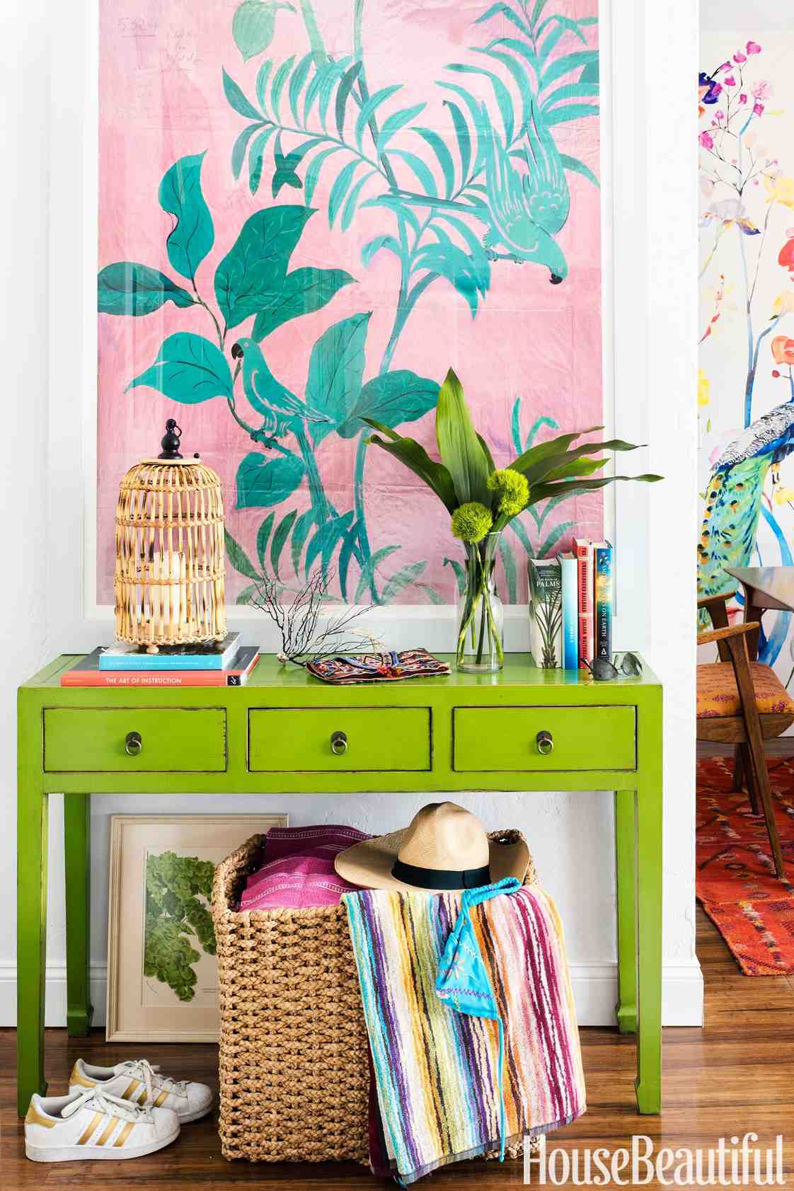 Schuyler Samperton's apartment entry with a green vintage console and a basket below; photograph credited to Annie Schlechter in House Beautiful.